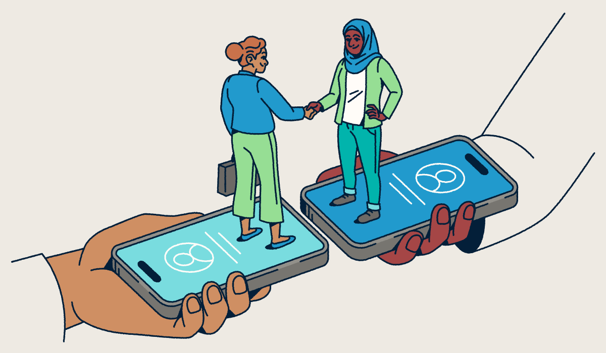 Two people standing on smartphones shaking hands.