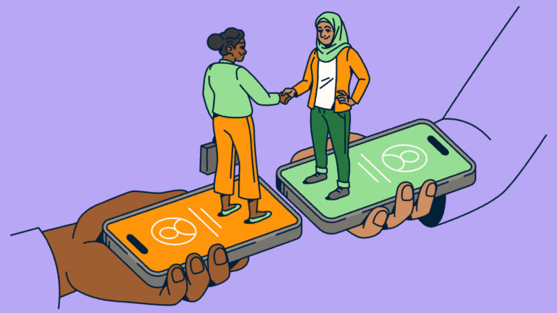 Two people standing on smartphones shaking hands.