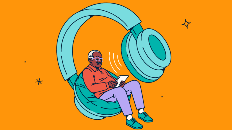 A person looking at a tablet while sitting in one side of a giant pair of headphones.