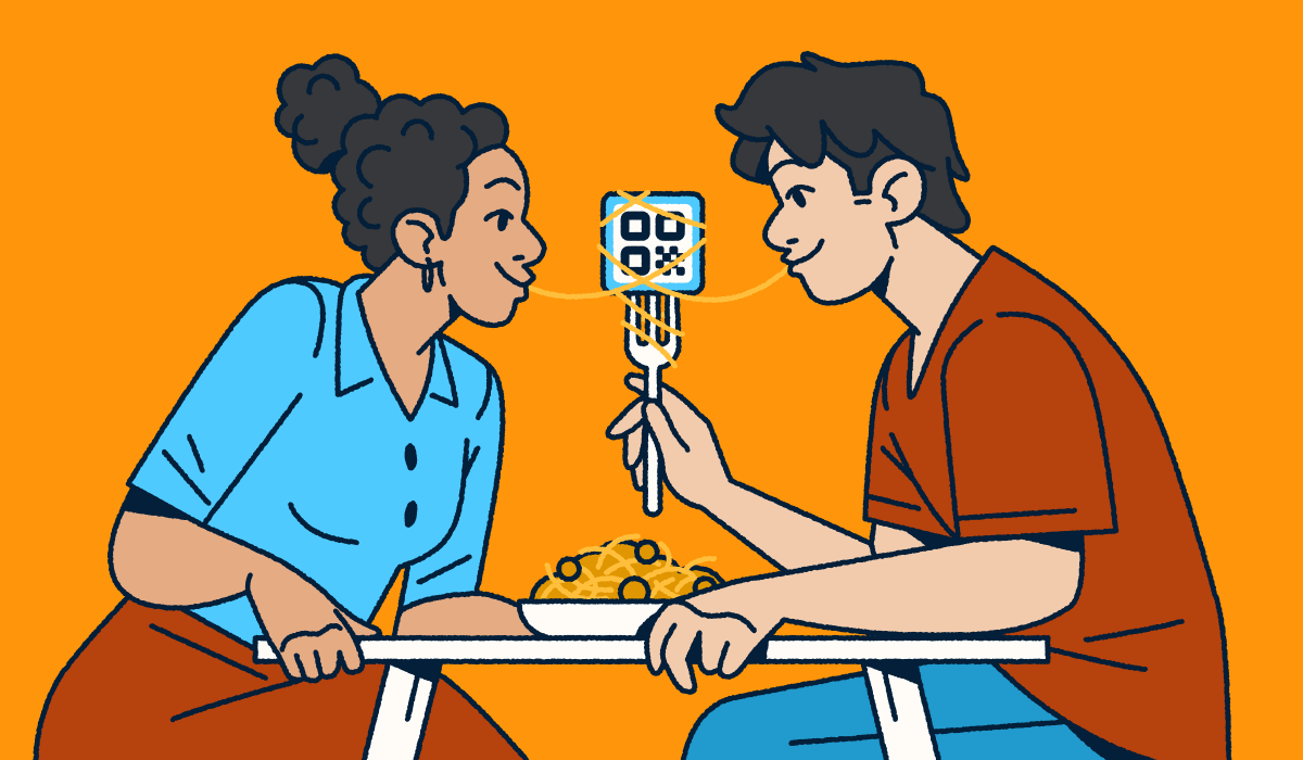 A couple sitting at a table sharing a bowl of spaghetti and meatballs. One partner is holding a fork with a QR Code on it and a piece of spaghetti wrapped around it. They each have one end of the noodle in their mouth.